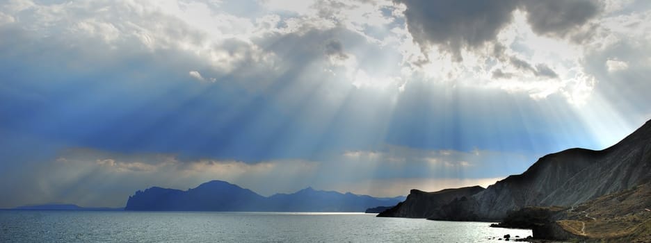 The sky and mountains. Gleams of the sun through dense overcast above mountains