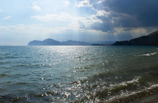 The storm sky above the sea with mountains on a background