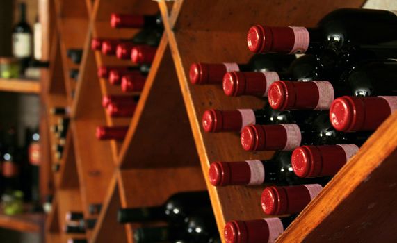 A buch of wine bottles in a rack in a wine cellar.