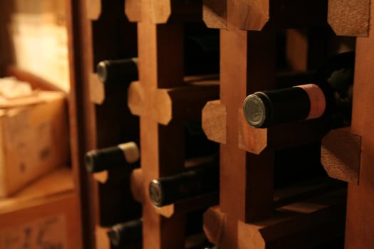 A bunch of wine bottles in a rack in a wine cellar.

