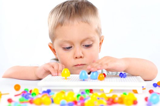 little boy playing with multicolored mosaic isolated on a white background