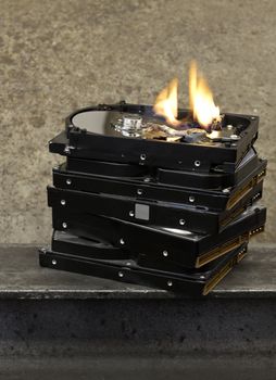 stack of hard drives with top one open and burning. 