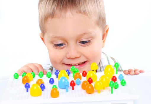 little boy playing with multicolored mosaic isolated on a white background