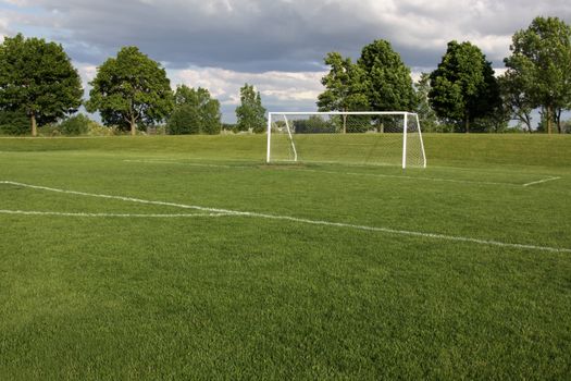 A view of a net on a vacant soccer pitch.
