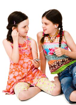 Girls listening to MP3 player and smiling isolated over white