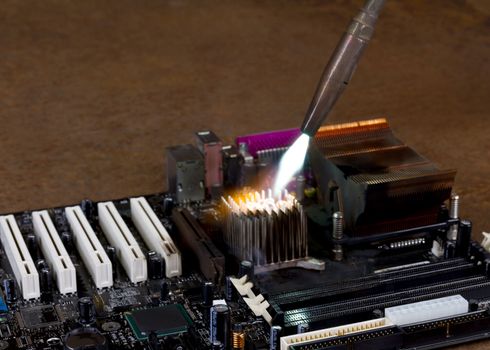 overheating a heat sink on a computer board with a welding torch in rusty background