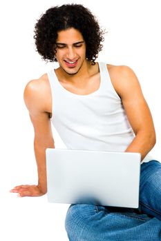 Smiling man using a laptop and posing isolated over white