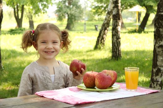 little girl with apple and juice in park