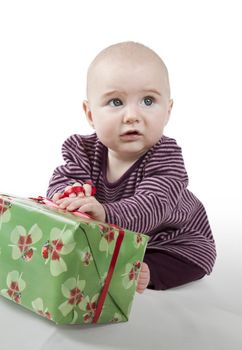 young baby sitting and holding gift looking alienated