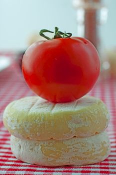 Tomato over two pieces of cheese over red and white cloth