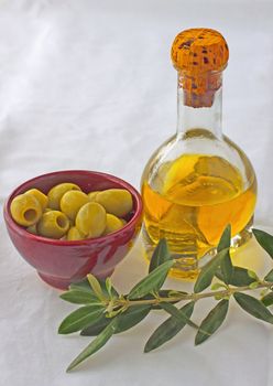 Olives in a cup, olive oil in a bottle and olive branch