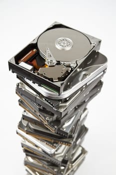 Stack of many different hard drives with opened drives on top. Grey background