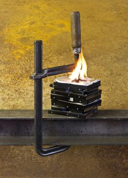 burning hard drives compressed with clamp in rusty background