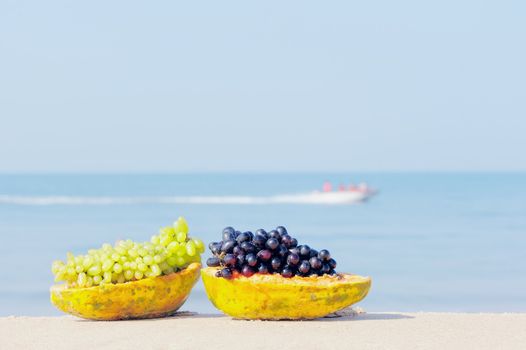 Tropical papaya and grape on the sandy shore