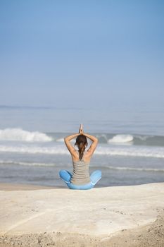 Beautiful young woman with arms open, relaxing on the beach