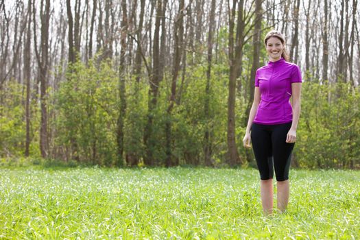 Beautiful fit girl standing in the meadow wearing sportsclothes