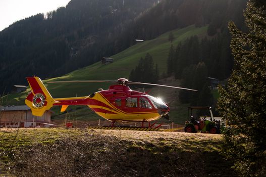 Side Of Grounded Yellow and Red Helicopter At Hangar