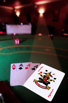 green casino table four aces in a poker game and a joker in the spotlight