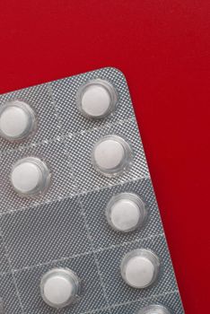 Macro view of white pills on red background.