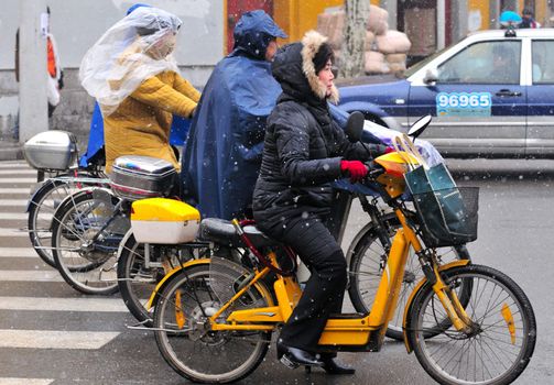 Chinese motorcyclist in shanghai street in a snowy day