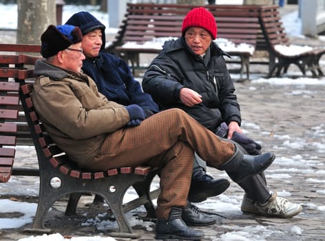  Chinese men sitting in Shanghai park in a winter day