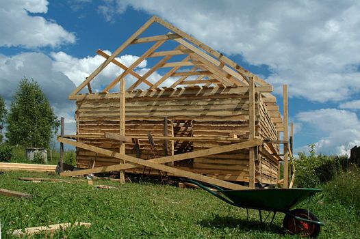 Building of a bath from a bar on a country site against the sky with clouds