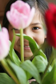 Child peeking through tulips