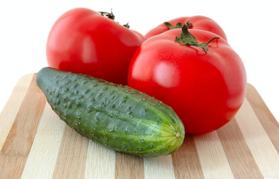 Vegetables (tomatos and cucumber) on bamboo cutting board.