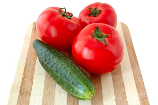 Vegetables (tomatos and cucumber) on bamboo cutting board.