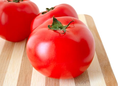 Vegetables (few tomatos) on bamboo cutting board.