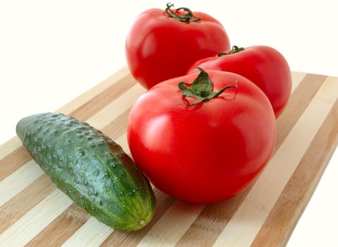 Vegetables (tomatos and cucumber) on bamboo cutting board.