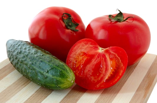 Vegetables (tomatos and cucumber) on bamboo cutting board.