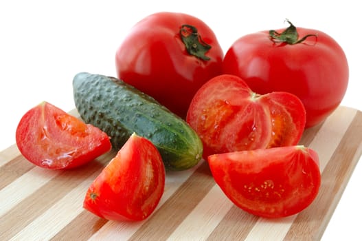 Vegetables (tomatos and cucumber) on bamboo cutting board.