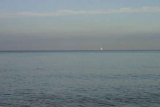 Small white sail on pastel silent sea