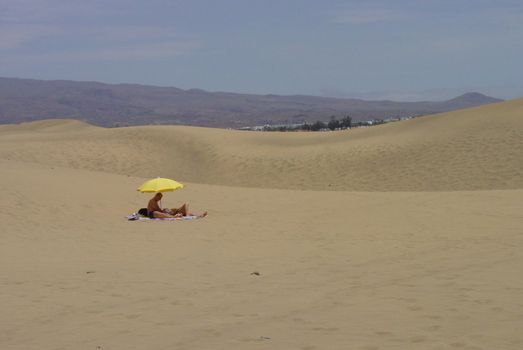 Yellow umbrella on desert in Gran Canaria dunes
