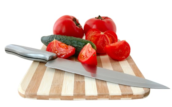Vegetables (tomatos and cucumber) with knife on bamboo cutting board.