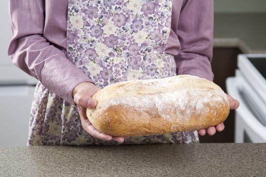 Woman wearing a apron holding a loaf of bread