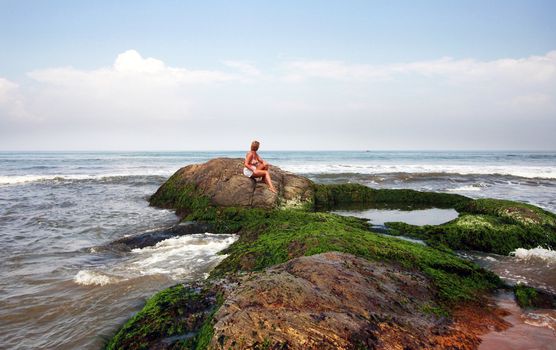 The woman sitting on a stone at ocean. Sri Lanka