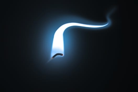 Close up on an ignited candle wick with extended blue flame against a black background.