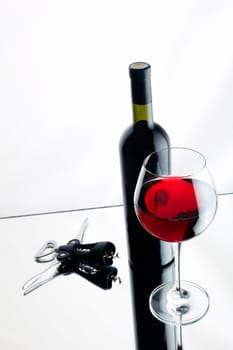 Still-life with bottle and glass of red wine over white background.