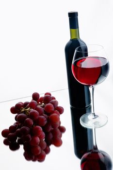 Still-life with bottle and glass of red wine over white background.