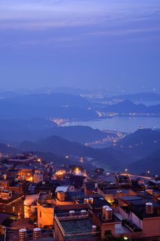 City night scene with houses on hill in yellow tone under blue sky in Jiufen(Jioufen), Taiwan, Asia.