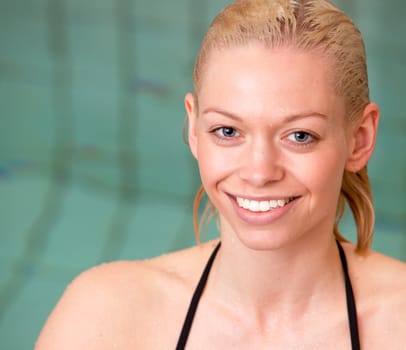 A portrait of a wet blond woman by an indoor pool