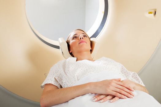 A horizontal image of a woman with eyes open taking a CT scan