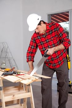 A wood worker using a hand saw in a home interior