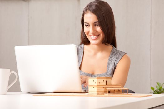 A designer or architect at desk with computer and model house