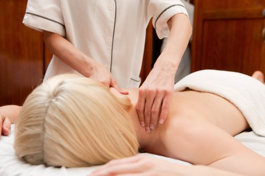 A woman in a retro styled spa receiving a shoulder massage