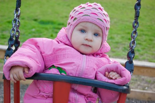 Blue eyed girl in pink on swing