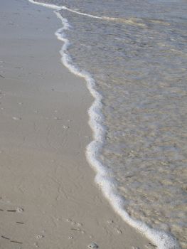 Last part of a wave slowly rolling on a sanding beach