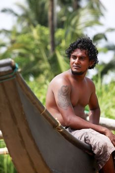 The young man sitting by a boat. Sri Lanka